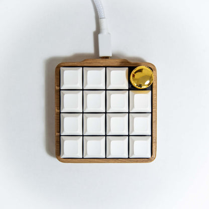 Klawos macropad with white white keycaps and gold knob on a light background
