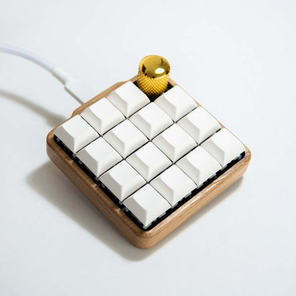 Small mechanical keyboard with white keys and wooden frame on a light background